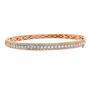 A modern bangle bracelet this rose gold bangle features three rows of round brilliant cut diamonds. In the center of the bangle, larger diamonds sparkle. Outside of the larger diamonds are two rows of smaller prong-set diamonds to compliment its brilliance. Give this diamond bangle for a special occasion gift that sparkles.